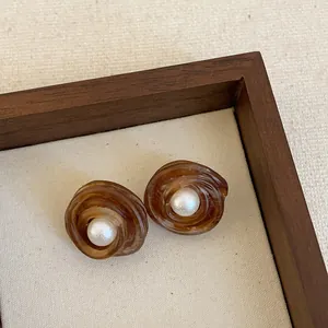 Close-up of vintage brown resin stud earrings with elegant white pearl center accents