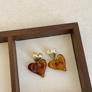 Close-up of elegant amber resin heart earrings with gold metallic texture