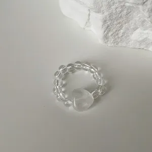 Close-up of translucent heart-shaped stone beaded elastic ring on white background