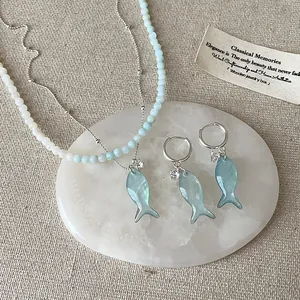 Dettaglio ravvicinato della collana e orecchini con pendente pesce azzurro su base