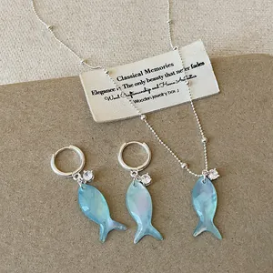 Collana con pendente a pesce in conchiglia blu e orecchini a cerchio coordinati.