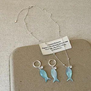 Dettaglio ravvicinato della collana con ciondolo pesce blu e set di orecchini coordinati
