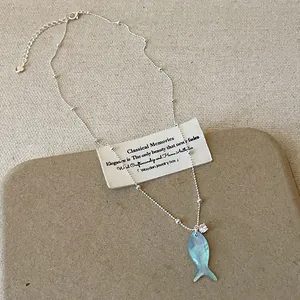 Dettaglio di una collana con ciondolo a forma di pesce in conchiglia blu e cristallo