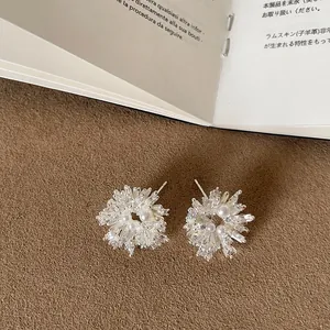 Close-up of elegant silver metal firework stud earrings with crystals and pearls
