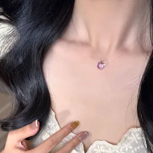 Nahaufnahme des minimalistischen rosa Kristallanhängers an einer unsichtbaren Kette