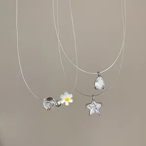 Makroansicht von Stern-, Tropfen- und Gänseblümchen-Anhängern an unsichtbarer Schnur.