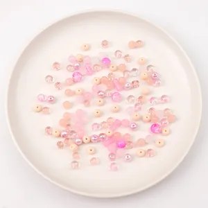 Assorted pink and peach glass beads for DIY jewelry making, including round and bamboo shapes.