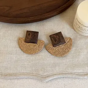 Detailed view of geometric handmade rattan and dark wood stud earrings on natural linen background