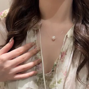 Minimalist pearl pendant necklace with invisible fish line worn on neck by a woman model