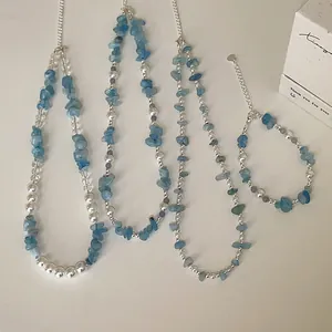 Gedetailleerd aanzicht van aquamarijnsteen en parel kralen ketting en armband set