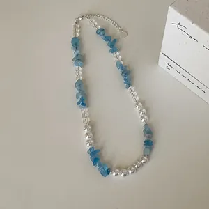 Detailopname van aquadmarijn natuursteen en parelkralen ketting op witte tafel