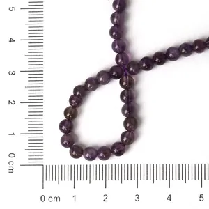 Macro view of natural amethyst round beads on centimeter ruler for size reference