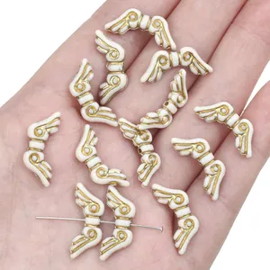 Detailed view of retro white acrylic angel wing beads with gold trim for DIY jewelry making