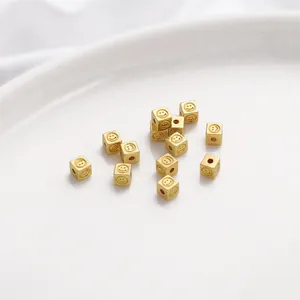 Close-up of small 14K gold-filled square spacer beads with engraved smiley faces