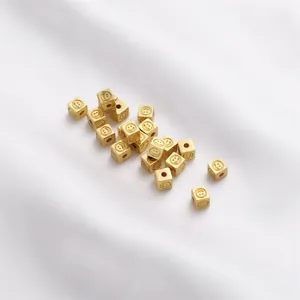Detail view of 14K gold-plated square beads with engraved smiley faces for DIY jewelry.