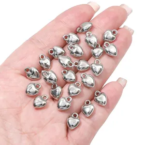 Detailopname van glanzende zilveren hartvormige bedels in een hand voor DIY sieraden