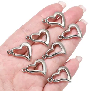 Close-up van zilveren hartvormige CCB-bedels in een hand voor het maken van sieraden