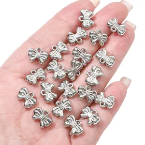 Detailopname van zilveren strik-bedeltjes in de hand voor DIY-kettingen en sieraden maken