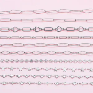 Sortiment an Edelstahlketten mit Herz- und Sternmotiven auf rosa Hintergrund für DIY-Schmuckbau