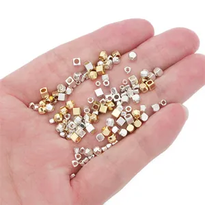 Mixed 14K gold and silver faceted square spacer beads for DIY jewelry making in hand.