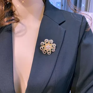 Nahaufnahme einer goldfarbenen Blumenbrosche mit Perlen auf einem schwarzen Blazer