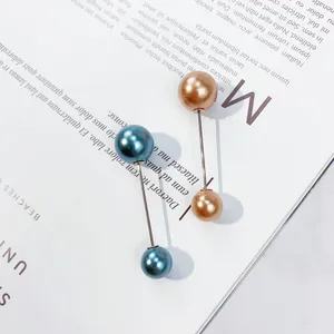 Detailansicht von zwei doppelköpfigen Perlenbroschen in Blau und Champagnergold-Finish.