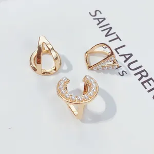 Nahaufnahme von goldfarbenen Schalschnallen mit eleganten Perlendetails auf weiß
