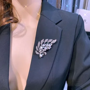 Detail einer eleganten Blattbrosche mit Perlen und Kristallen auf schwarzem Blazer
