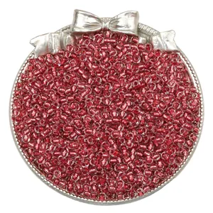 Macro detail of red silver-lined glass seed beads in a decorative silver bow tray