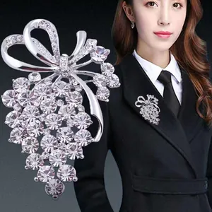Elegant silver-colored crystal grape brooch with bow detail shown on a black woolen coat
