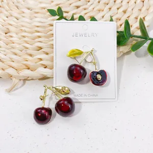 Macro detail of high-quality cute red cherry brooch pin with gold stem and leaves