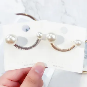 Close-up detail of minimalist gold and silver U-shaped pearl brooches for clothing accents