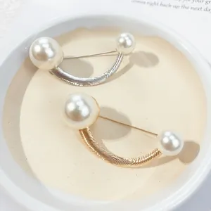 Elegant close-up of U-shaped pearl brooches in gold and silver tones for clothing