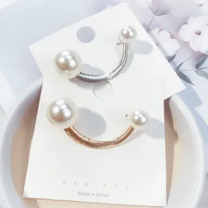 Detail view of U-shaped gold and silver pearl brooches for cardigan styling.