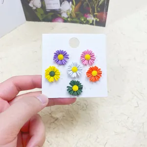 Close-up of six colorful daisy-shaped safety pins and brooches for shirt collars