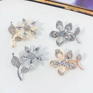 Detailansicht von vier eleganten Kristall-Blumenbroschen in Gold und Silber.
