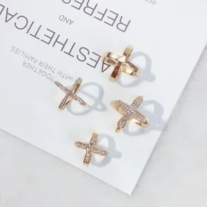 Elegante goldene X-förmige Strass-Schalringe und Schnallen auf ästhetischem Hintergrund.