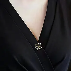 Nahaufnahme einer goldenen vierblättrigen Kleeblatt-Brosche an einem schwarzen Kleid