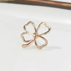 Makroaufnahme einer roségoldenen hohlen Vierblatt-Kleeblatt-Brosche auf weißem Grund.