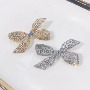Nahaufnahme funkelnder Kristall-Strass-Schleifenbroschen in Gold und Silberoptik