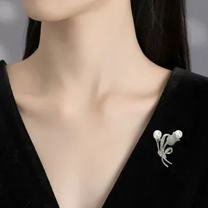 Detailansicht einer eleganten floralen Perlenbrosche auf einem schwarzen Samtkleid