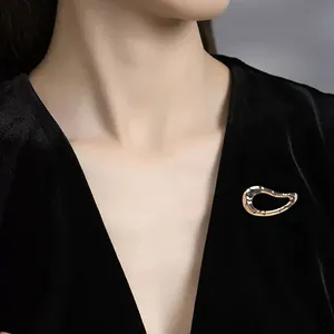 Minimalistische vergoldete geometrische Brosche auf eleganter schwarzer Samtkleidung