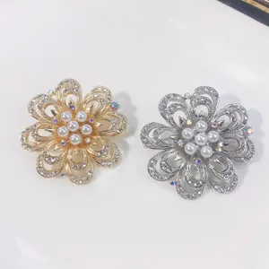 Detailansicht eleganter gold- und silberner Blumenbroschen mit Perlen und Kristallen.