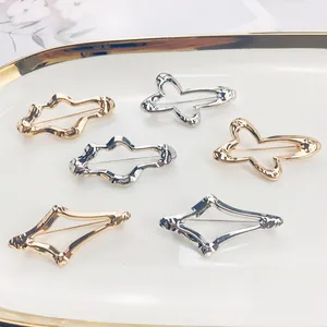 Nahaufnahme von minimalistischen geometrischen Legierungsbroschen in Gold und Silber