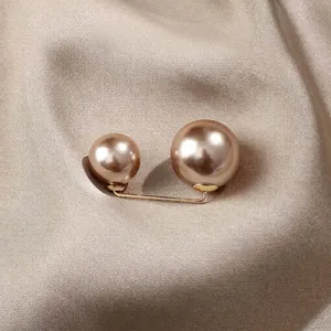 Elegant champagne faux pearl brooch pin for waist adjustment on silk background texture