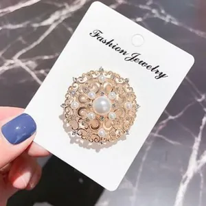 Detailansicht einer eleganten floralen Perlenbrosche mit Kristallen auf Displaykarte.