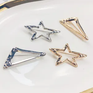 Nahaufnahme von minimalistischen gold- und silbernen hohlen Stern- und Dreieck-Broschen