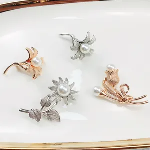 Makroaufnahme von vier Vintage-Legierungsblumenbroschen mit eleganten weißen Perlen