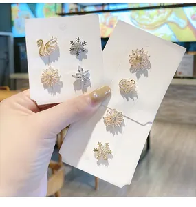 Nahaufnahme eleganter kristallbesetzter Broschen in Schwan- und Schneeflockendesigns