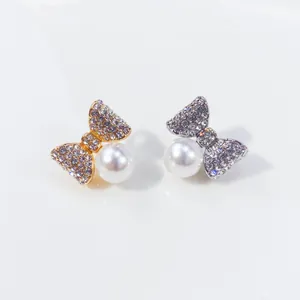 Detailaufnahme eleganter Strass-Schleifenbroschen mit weißen Perlen in Gold und Silber finish